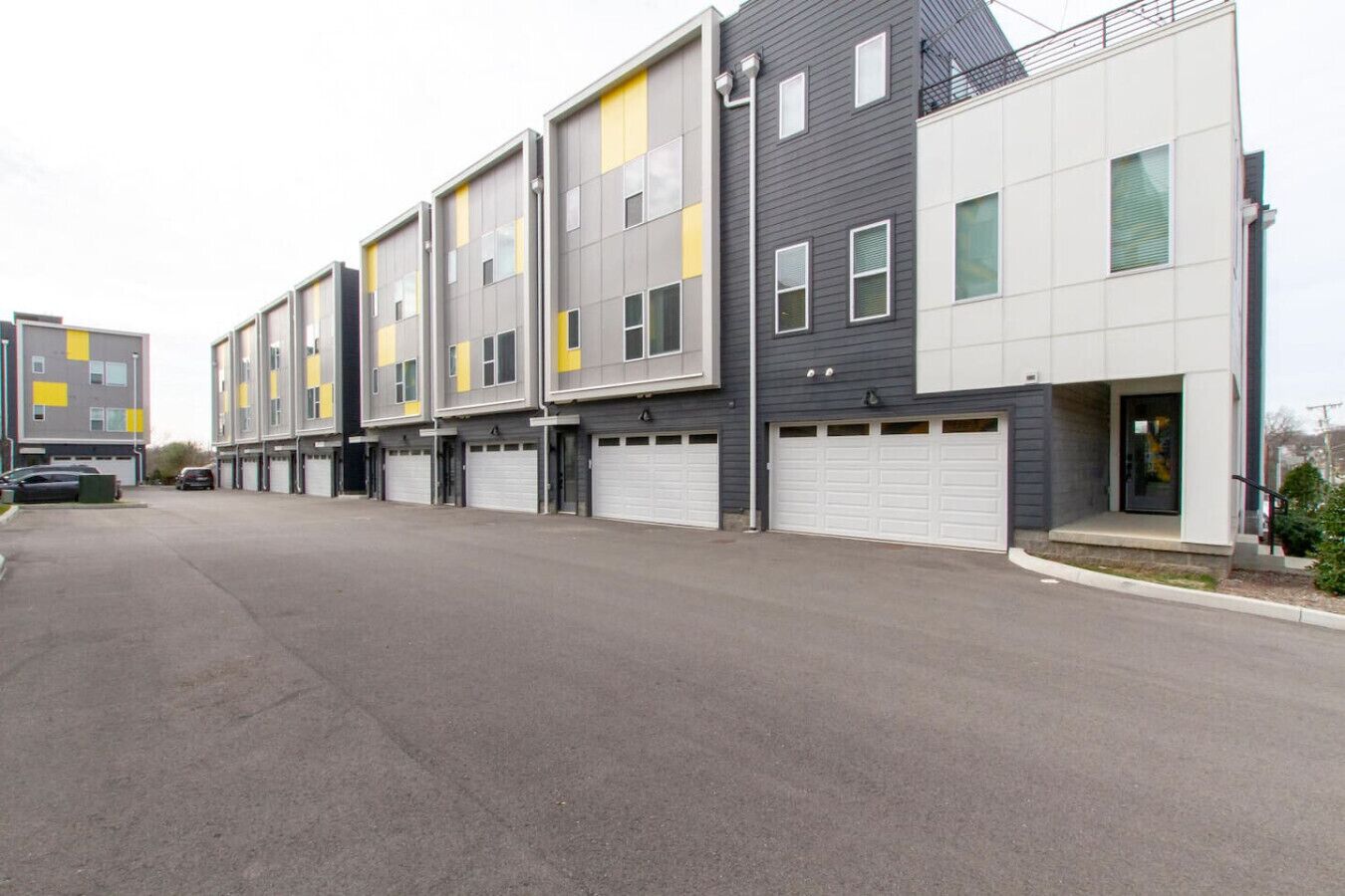 A row of modern multi-story buildings with garage doors, likely residential or mixed-use.