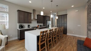 A modern kitchen with dark cabinets, a central island, and pendant lighting. - Two Townhomes - Hot Tubs and Rooftop Balconies (Nashville)
