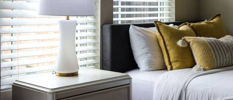 A neatly made bed with white bedding, a bedside lamp, and decorative pillows.