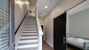 Un escalier menant à une chambre à coucher qui contient un lit, une armoire et une porte.