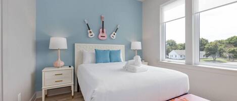 A bedroom with a bed, bedside tables, a window, and guitars on the wall.