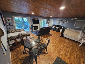 Una sala acogedora con un sofá, un sillón, una mesa de vidrio y un televisor.
