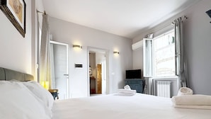 A hotel room with a large bed, a television, a bathroom, and a view of the outdoors. - Solemar Sicilia - Valuan Luxury Home (Palermo)
