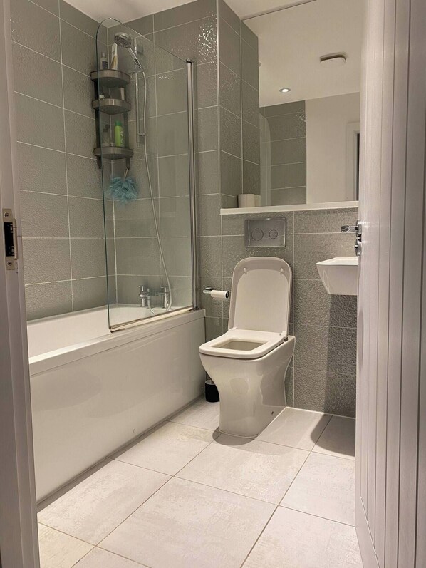A modern bathroom with a glass-enclosed shower, a white toilet, and a sink.