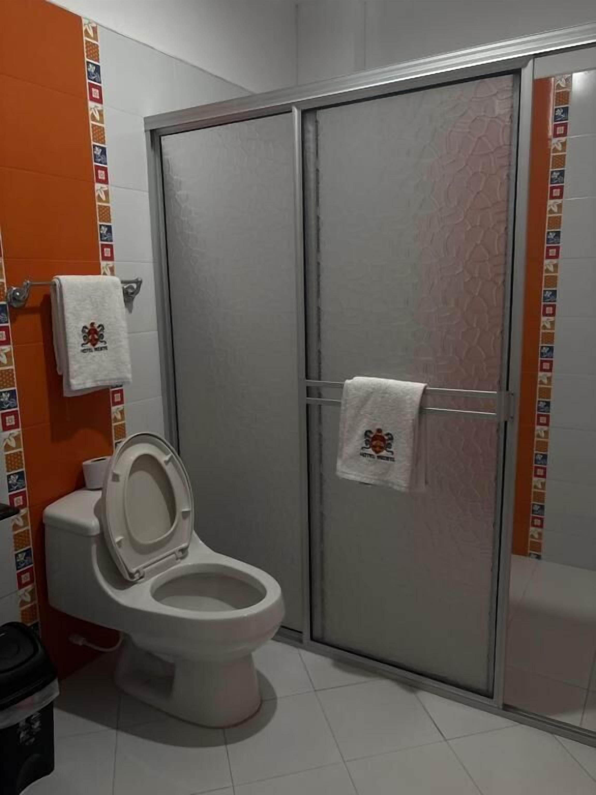 Ein Badezimmer mit Toilette, Duschkabine und Handtuchhalter.