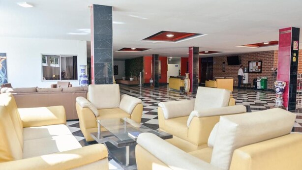 A lobby with yellow sofas, a checkered floor, and a brick wall. - Hotel Beijing Caucasia (Caucasia)