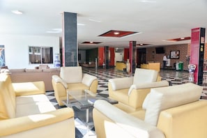 Un hall con sofás amarillos, suelo a cuadros y pared de ladrillo.