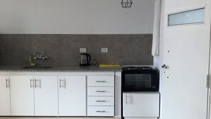Una cocina moderna con armarios blancos, cafetera y microondas.