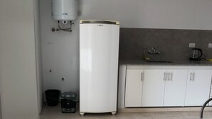 Una cocina compacta con armarios blancos, un lavamanos integrado y un refrigerador.