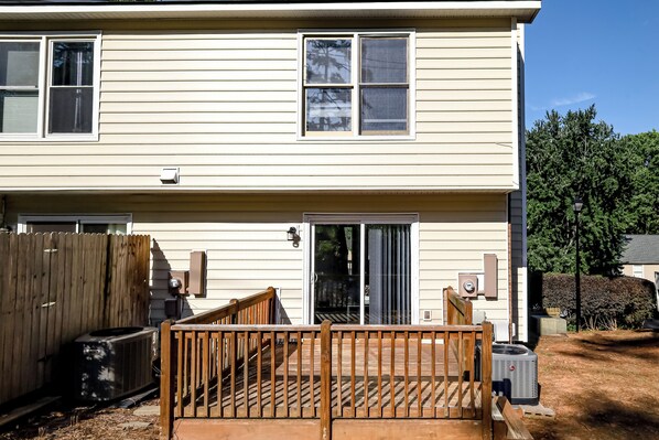 A two-story house with a wooden deck, a sliding glass door, and a fenced backyard. - Karen's Place- Centrally located near RDU, Downtown, North Hills and more! (Raleigh)