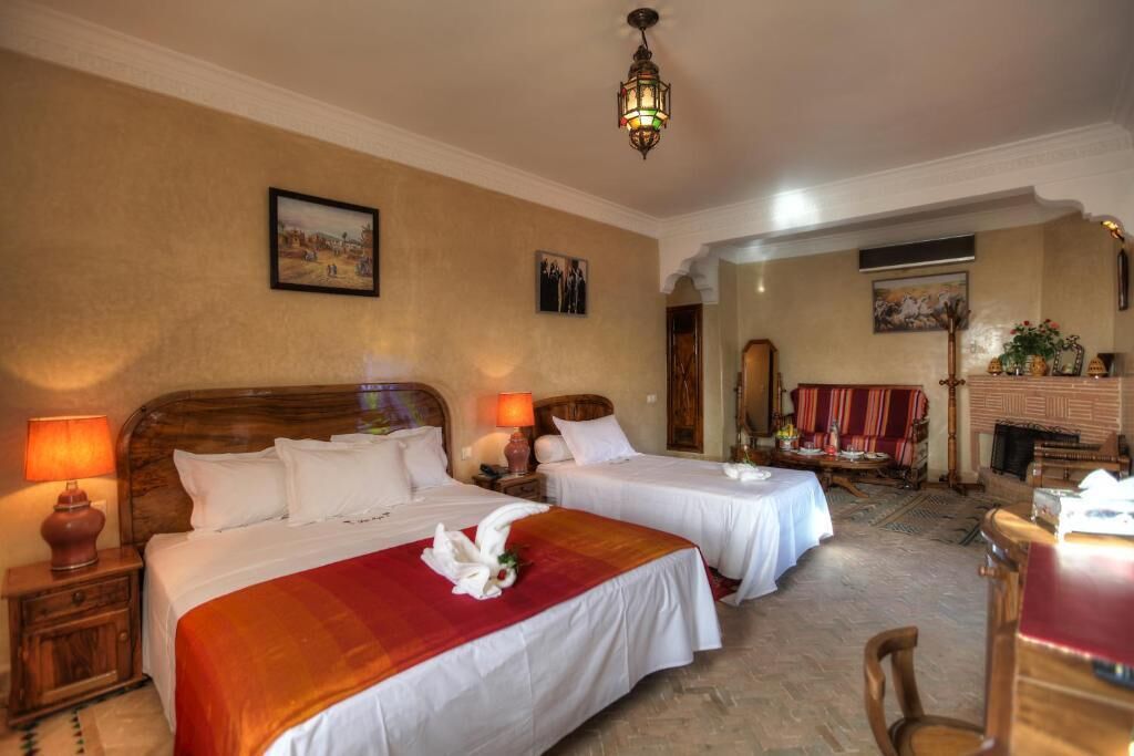 Une chambre d’hôtel avec deux lits, une tête de lit en bois, une cheminée et un coin repas.