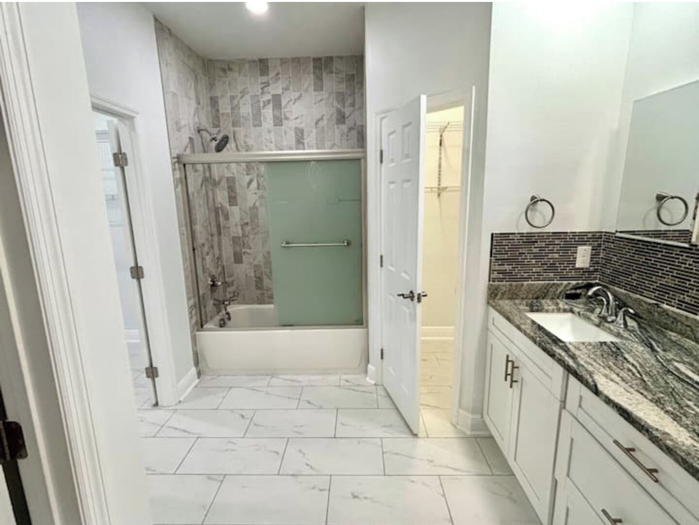 Ein Badezimmer mit Dusche, Badewanne und Waschbecken mit einer Naturstein-Arbeitsplatte.