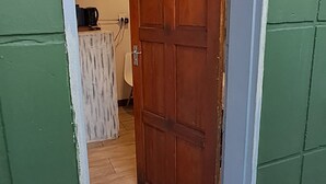 A wooden door with the number 3, leading into a room with a white wall and a patterned curtain.
