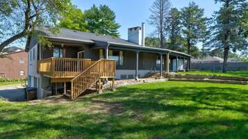 A two-story house with a wooden deck and a chimney.