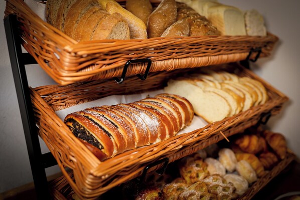 Deux paniers en osier remplis de différents types de pain et de pâtisseries.