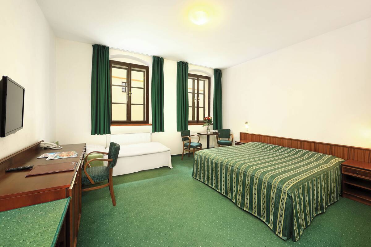 Une chambre d’hôtel comprenant un lit, un bureau, une chaise, une petite table et un téléviseur.