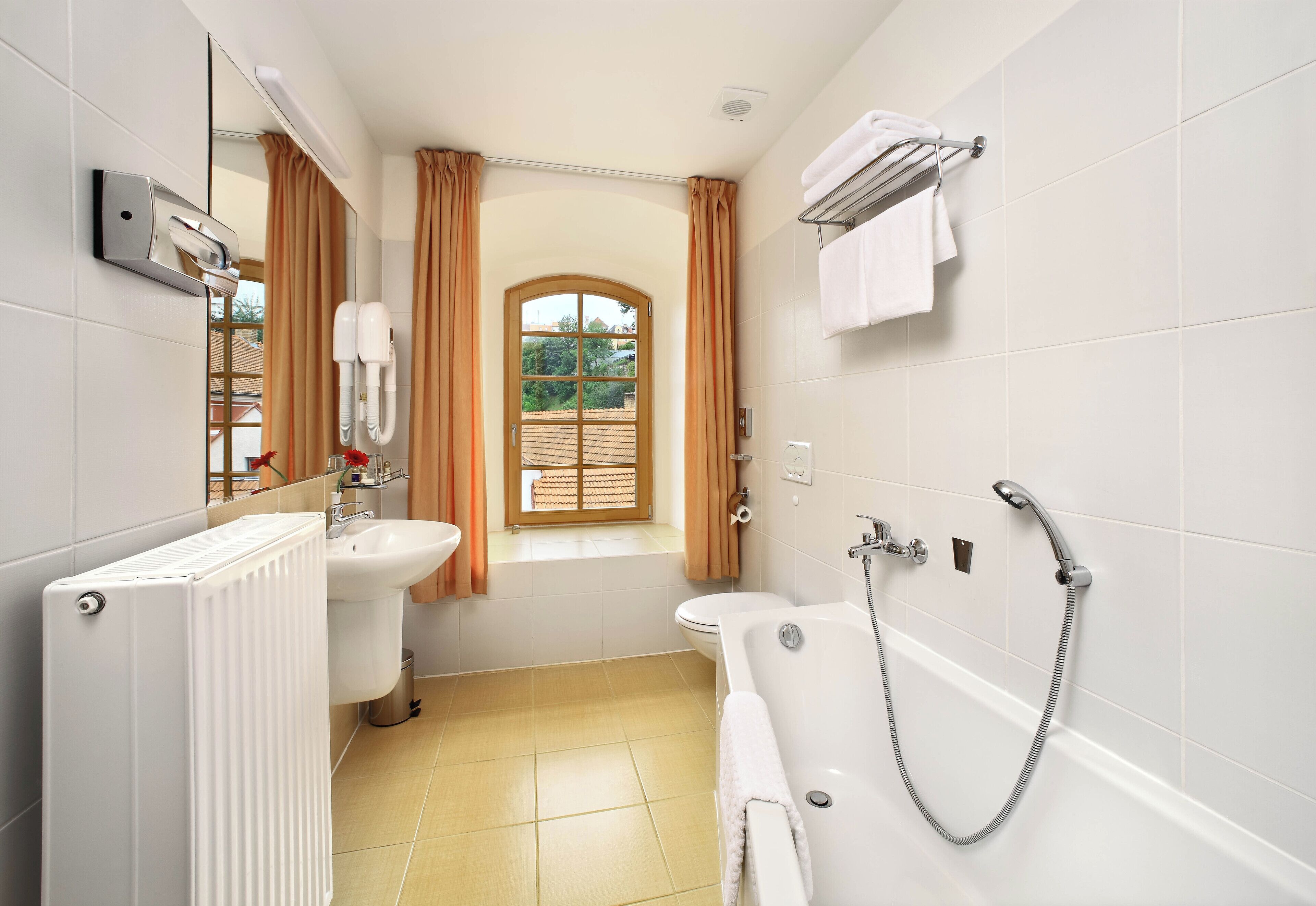 Un baño con radiador, lavamanos, inodoro y bañera.