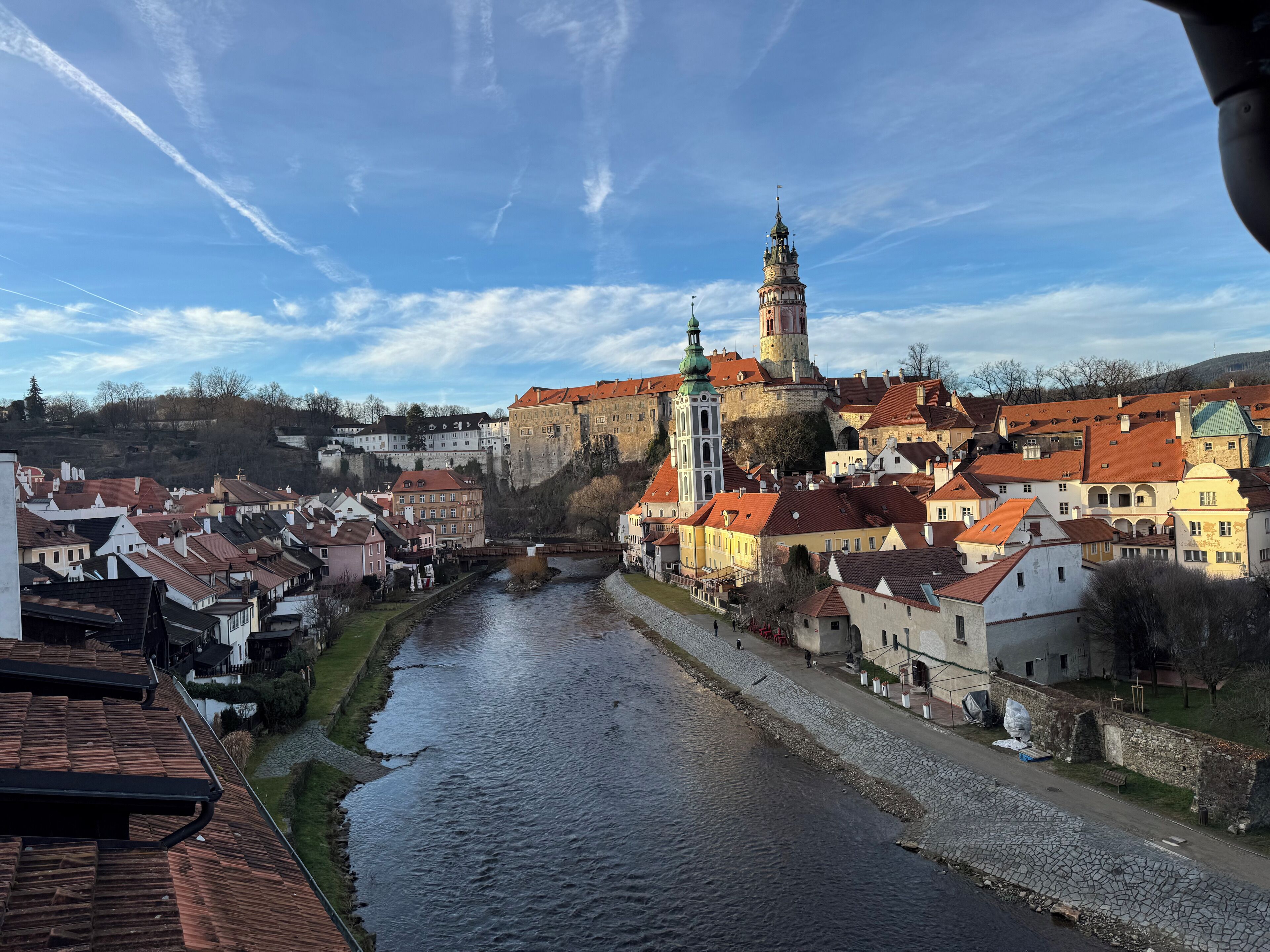 A river flowing through a town with historic buildings and a prominent tower.