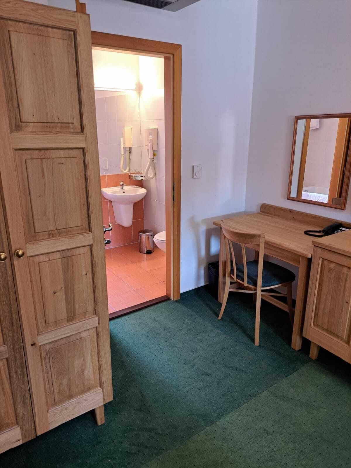 A wooden door leading to a bathroom with a sink, mirror, and toilet.
