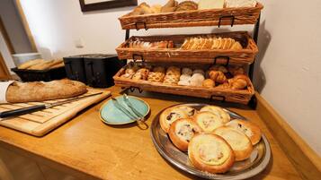 A buffet with various breads and pastries displayed on a wooden counter.