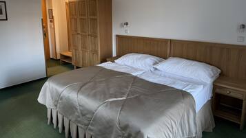 Un dormitorio con cama, armario de madera, mesitas de noche y alfombra verde.