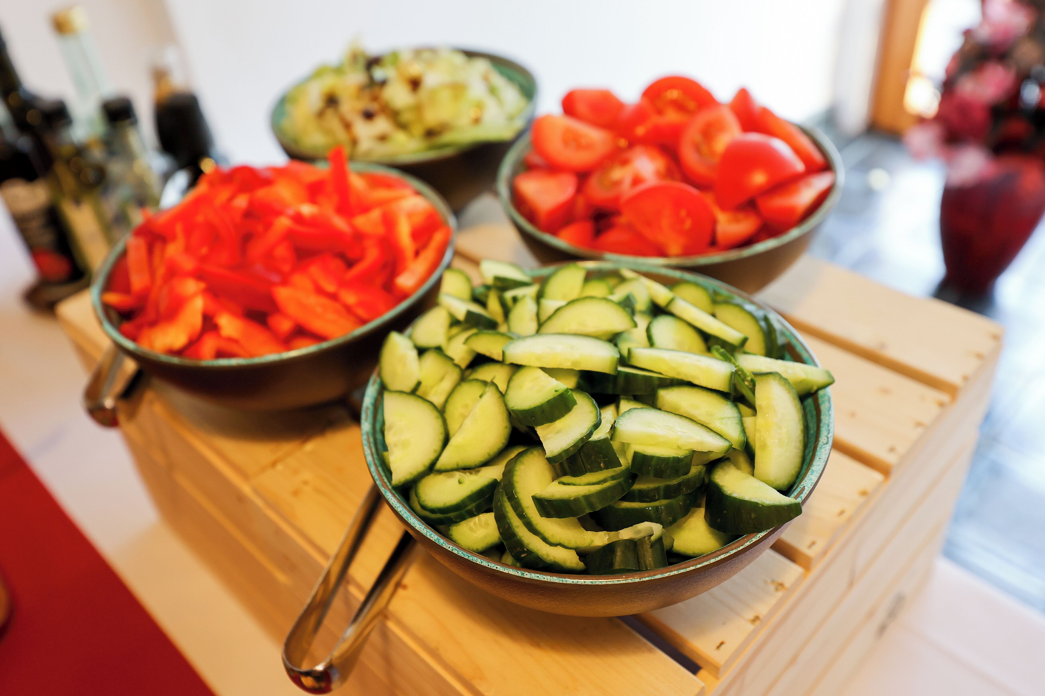 Una mesa de madera con tres recipientes que contienen verduras en rodajas.