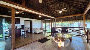 Une pièce spacieuse avec un plafond en bois, un coin repas comprenant une table et des chaises, et une grande fenêtre donnant sur l’extérieur.
