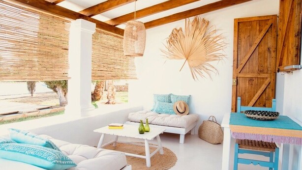 A bright, airy room with a white sofa, a small table, and a wooden door.