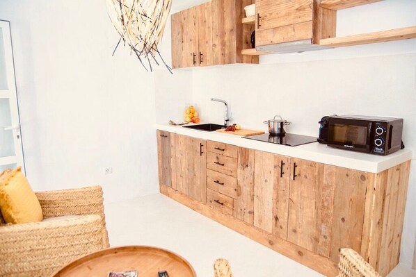 A compact kitchen with wooden cabinets, a sink, and a microwave. - Can Petit - Romantic & Cozy Villa (Formentera)