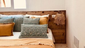 A bed with patterned pillows, a woven basket, and a wooden headboard.
