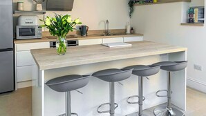 Een moderne keuken met een centraal eiland, barstoelen, een magnetron en een ingebouwde oven.