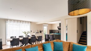 Ein modernes Wohnzimmer mit Sofa, Essbereich, Küche und einer Treppe.