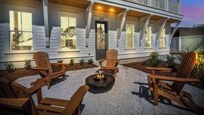 A house with a porch, numbered 217, and outdoor seating with chairs and a fire pit.