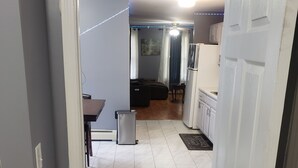 A hallway leading to a living area with a sofa, a small table, and a refrigerator. - The Silhouette! Chic 1-bedroom with WiFi and AC in serene Hartford (Hartford)