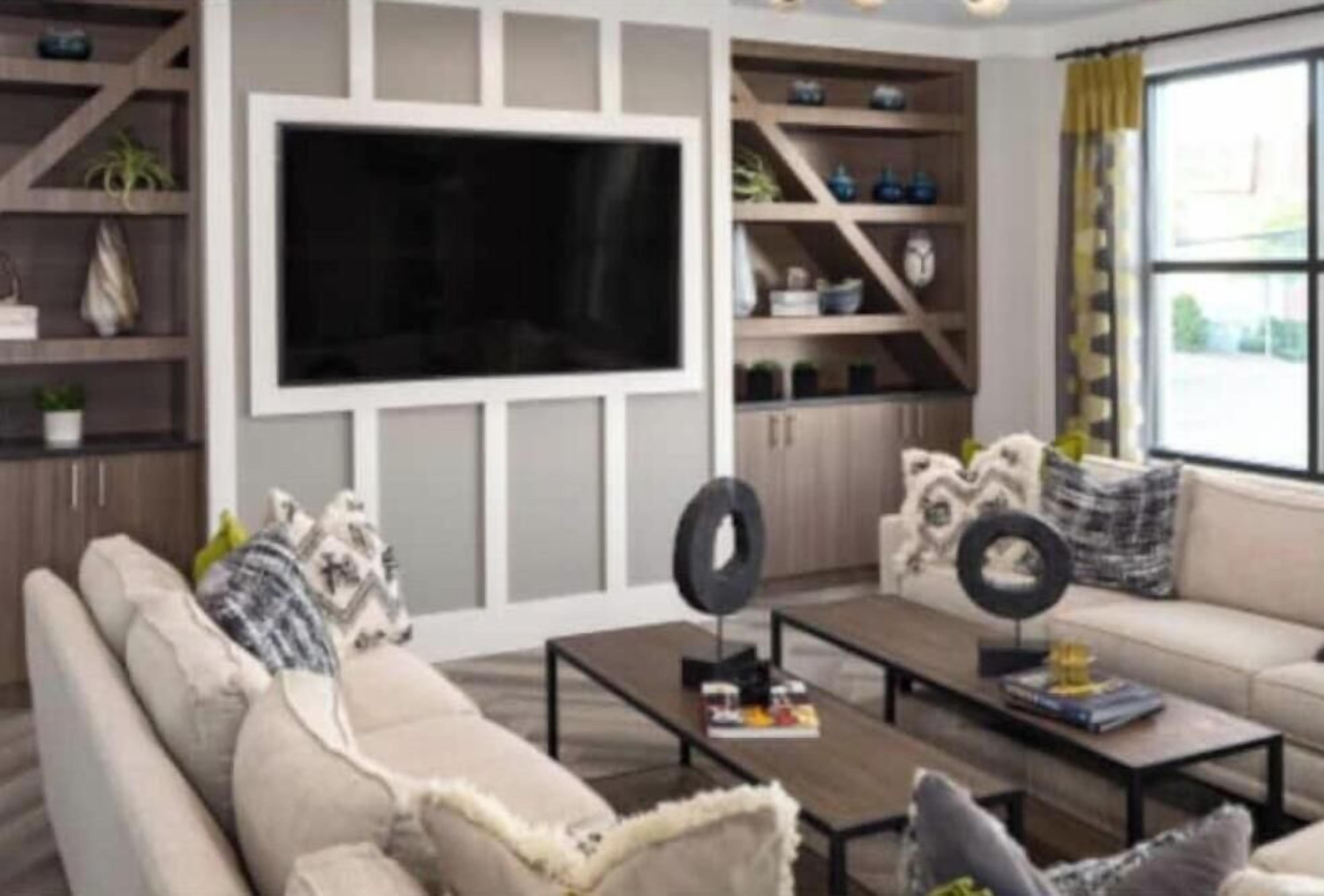 A modern living room with a large flat-screen TV mounted on the wall, a sofa with decorative pillows, a coffee table, and shelves with various items.