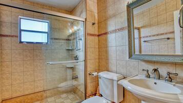 A bathroom with a glass-enclosed shower, a toilet, and a sink.