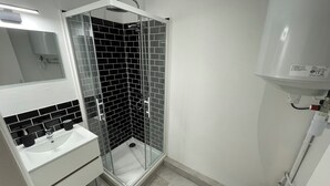A modern bathroom with a glass-enclosed shower, a white sink, and a toilet.