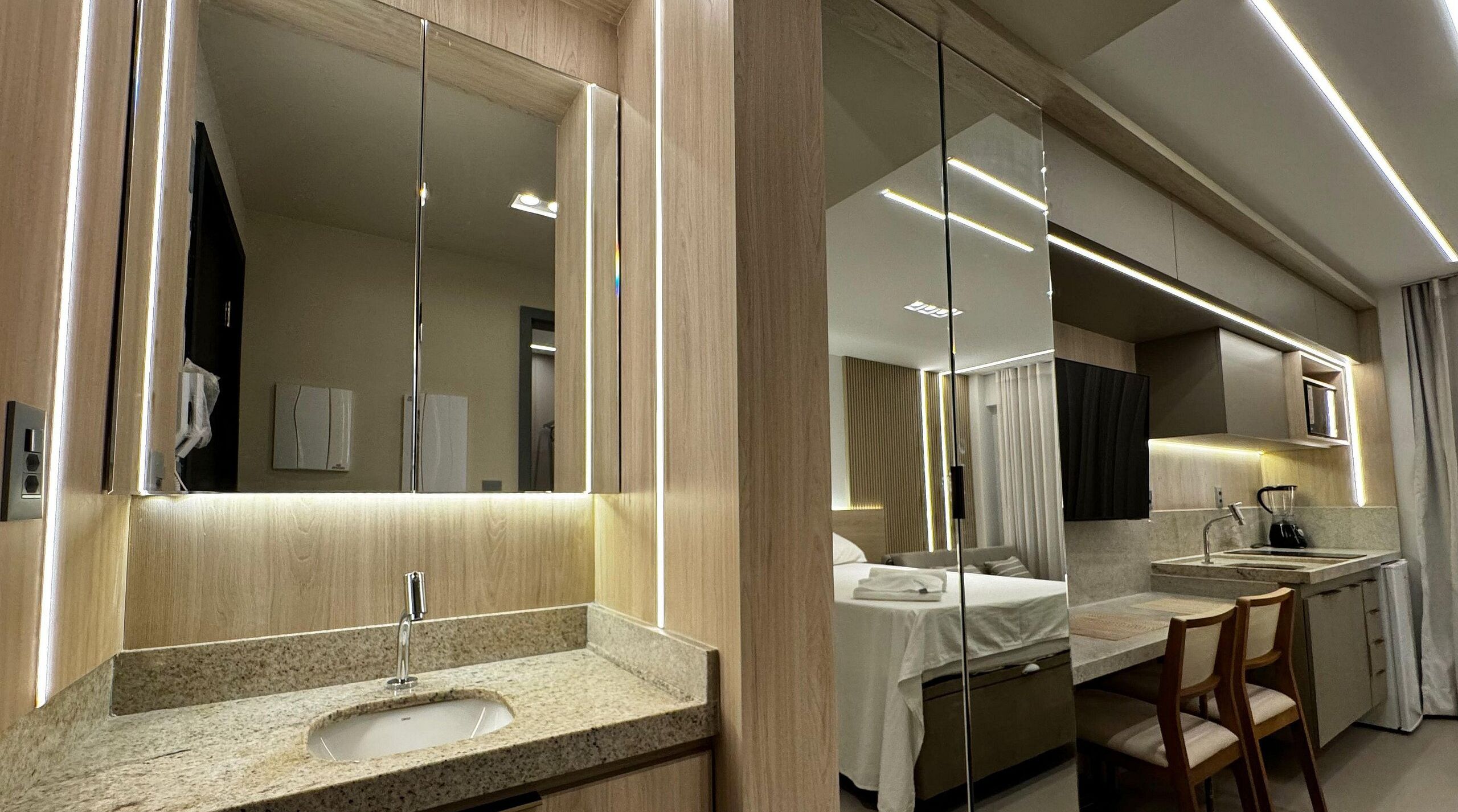 Une salle de bain d’hôtel moderne, dotée d’un grand miroir, d’un lavabo et d’un espace douche.