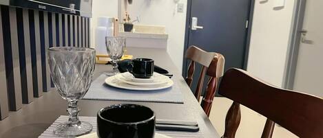 A dining table with plates, a glass, and a black mug, set with a placemat.