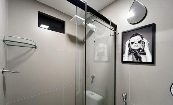 Een moderne badkamer met een douchecabine van glas, een toilet en een inlijsting foto aan de muur.