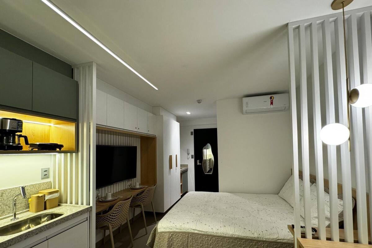 A compact hotel room with a kitchenette, a bed, a dining area, and a bathroom.