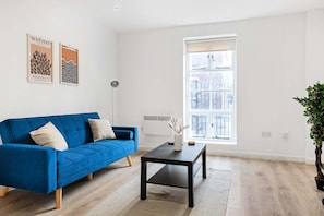 A modern living room with a blue sofa, a black coffee table, and a large window.