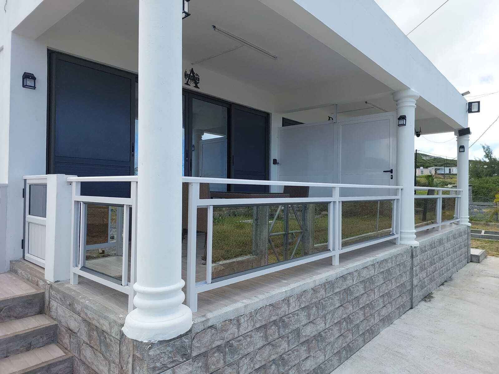 A building with a covered porch, stone steps, and a metal railing.