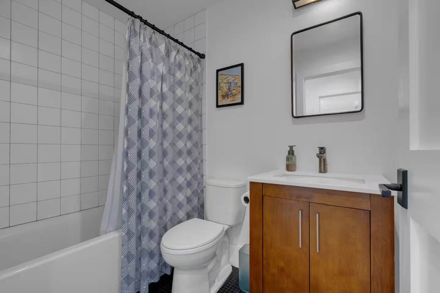 Une salle de bain avec un rideau de douche, des toilettes et un meuble en bois surmonté d’un miroir.
