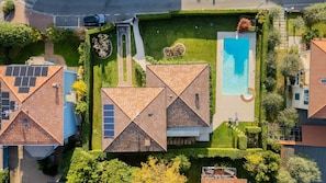 Vue aérienne d’un quartier résidentiel avec plusieurs maisons, une piscine et un jardin bien entretenu.
