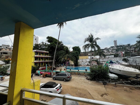 A view of a residential area with a swimming pool, parked cars, and a boat. - Casa De Huéspedes Walton (Acapulco)