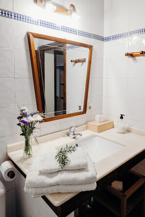 A bathroom with a white sink, mirror, and towel stack. - La Rectoral (Pilona)