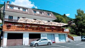A two-story building with a balcony, a car parked in front, and a sign that reads "NUOVA GESTIONE". - Al Maniero (Ponte di Legno)