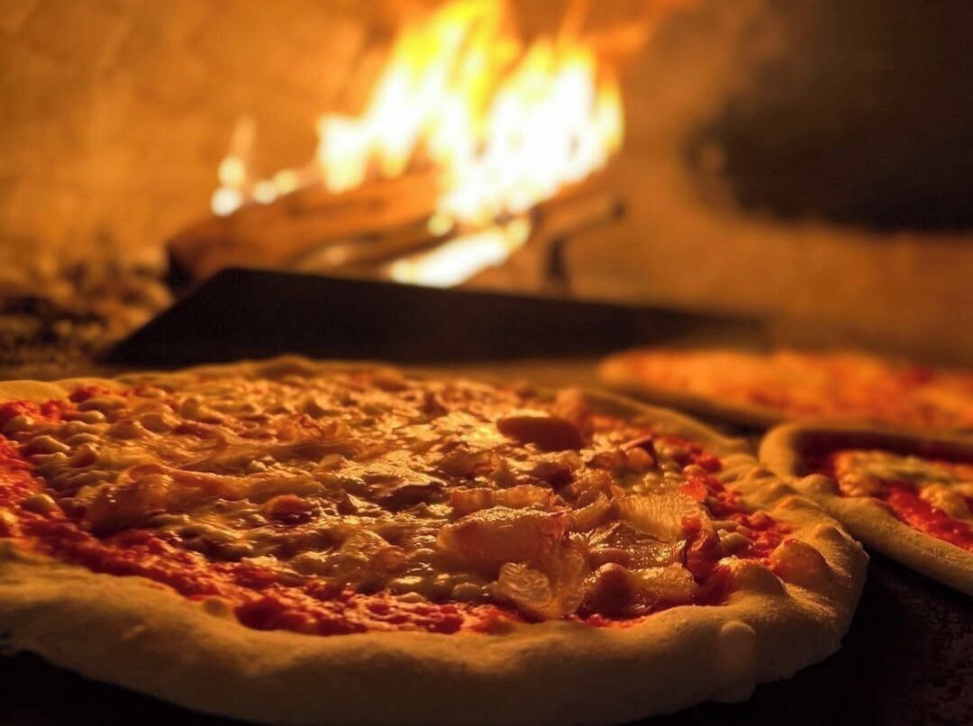 Un horno de pizza con pizzas en cocción.