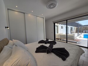 Een moderne slaapkamer met een groot bed, een schuifdeur en uitzicht op een buitenzwembad.
